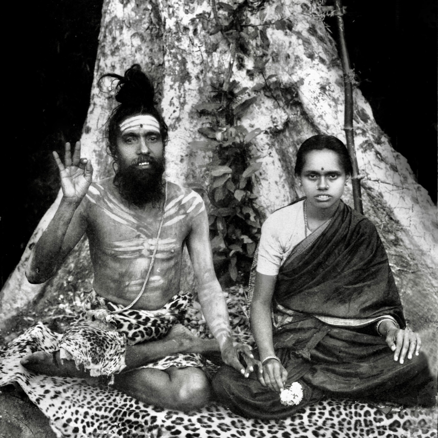 Pujyaśrī Devinatha Gurudeva and Pujyaśrī Devi seated beneath a tree
