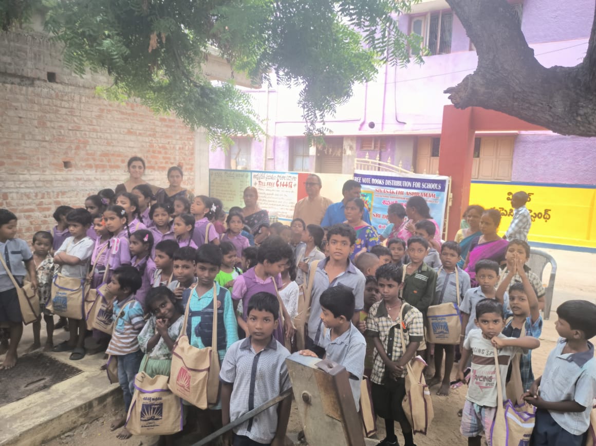 Schoolchildren gathered outdoors holding bags of school supplies