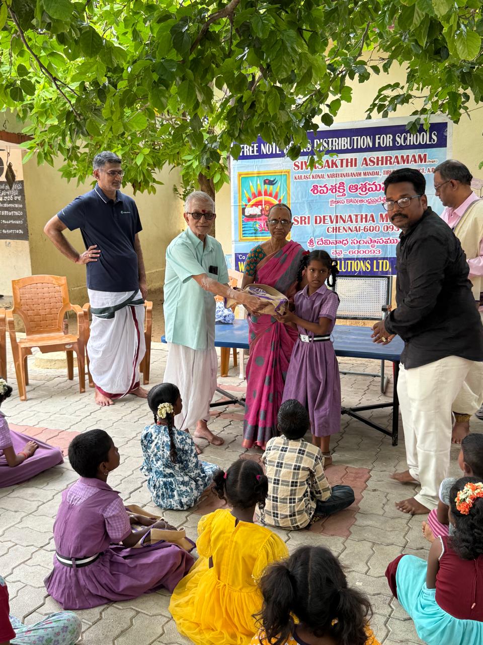 Adults presenting a school supply bag to a student in uniform