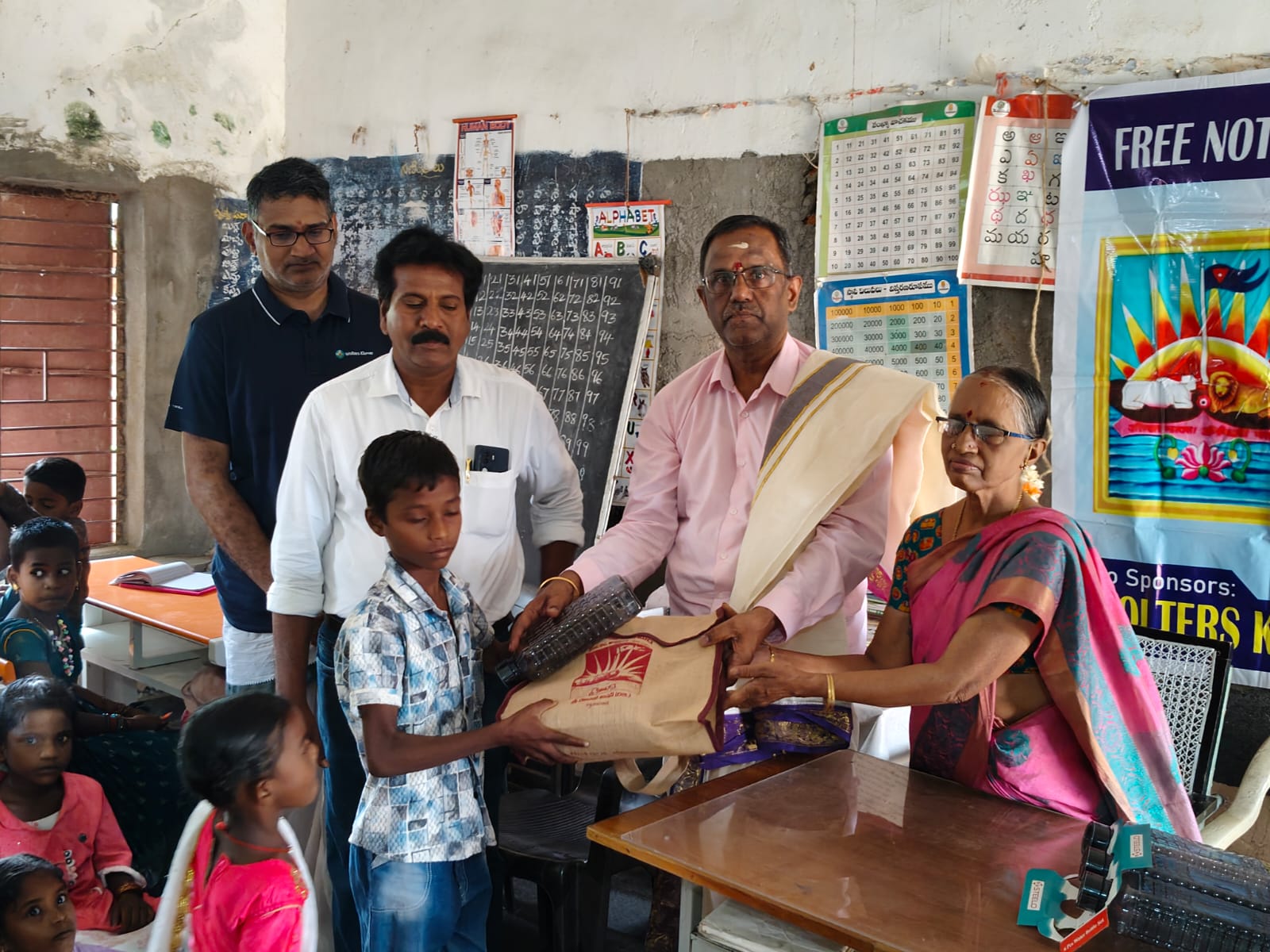 A schoolchild receiving a bag and learning materials from adults