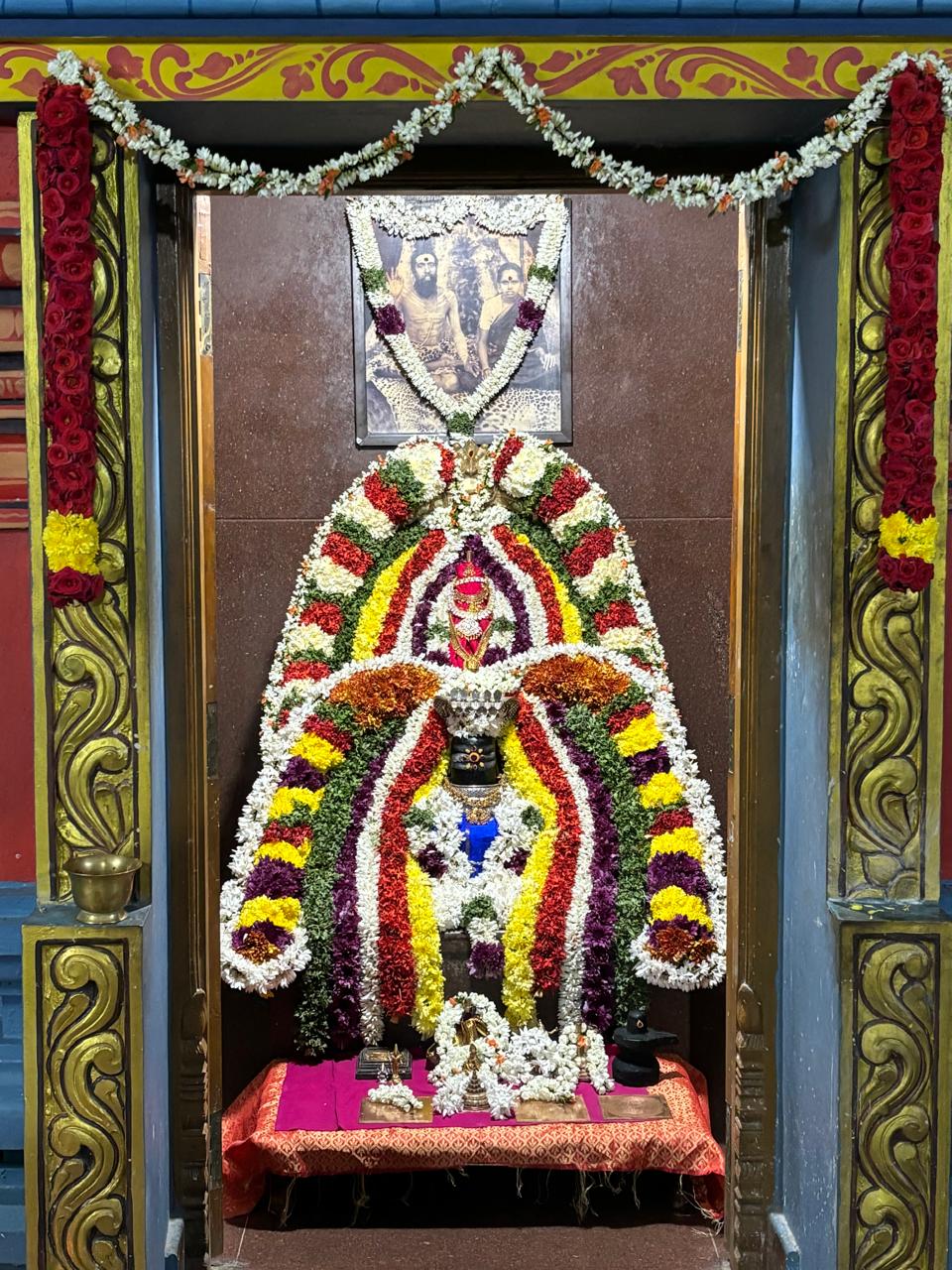 A flower-decorated shrine with a garlanded portrait above it