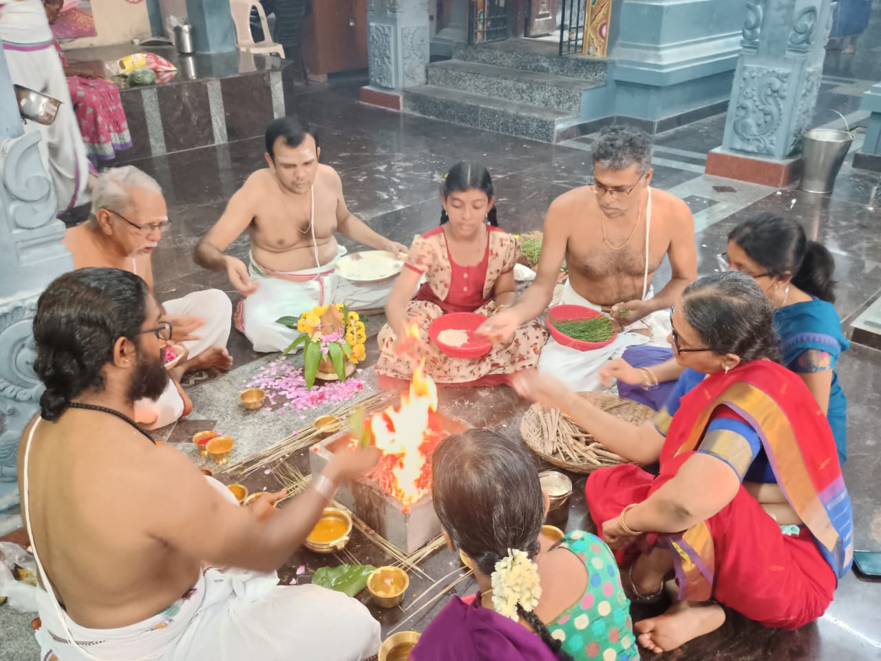 Women and men seated around a sacred fire inside the temple