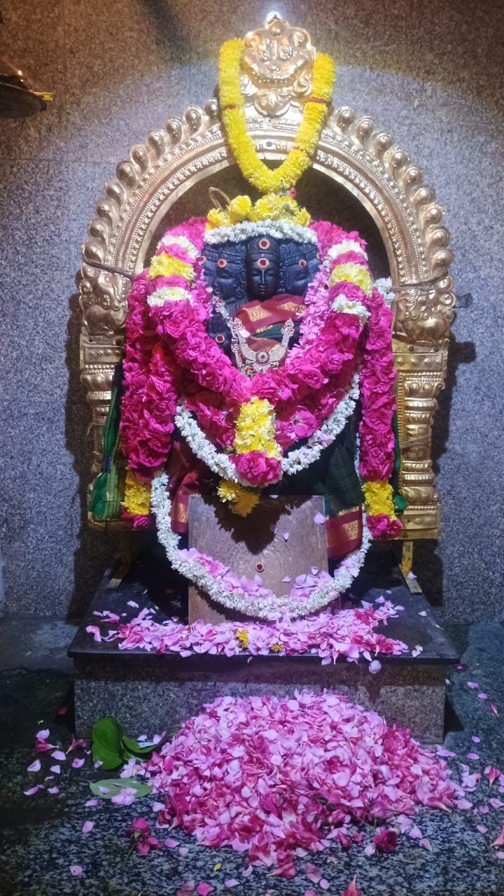 A shrine richly adorned with pink, white and yellow flowers